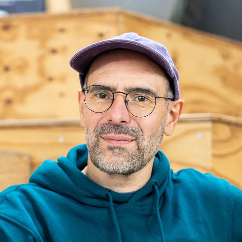 Thomas Binroth, Ernährungscoaching für Freizeitsportler bei Foodtrition, sitzt entspannt vor einem Holzhintergrund